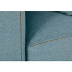 Close-up of blue denim upholstery with detailed stitching on a modern sofa cushion corner.