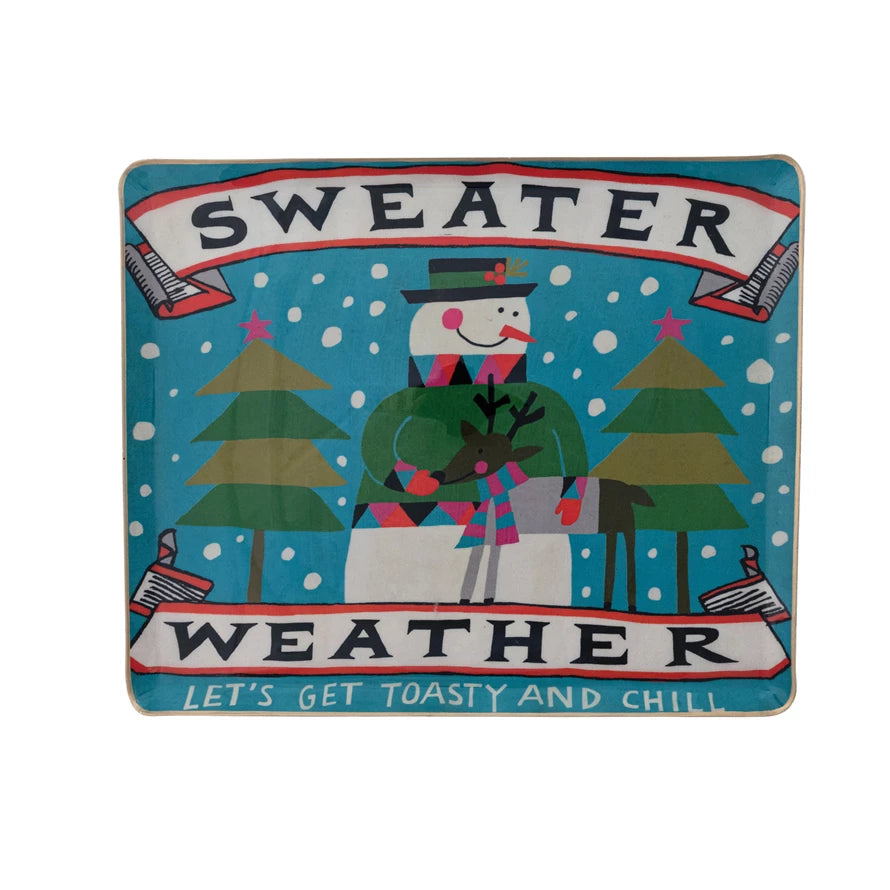 Metal tray with a snowman wearing a sweater holding a deer, surrounded by pine trees and snowfall design