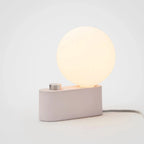 Minimalist modern lamp with a glowing round LED bulb and a dimmable control on a rectangular base