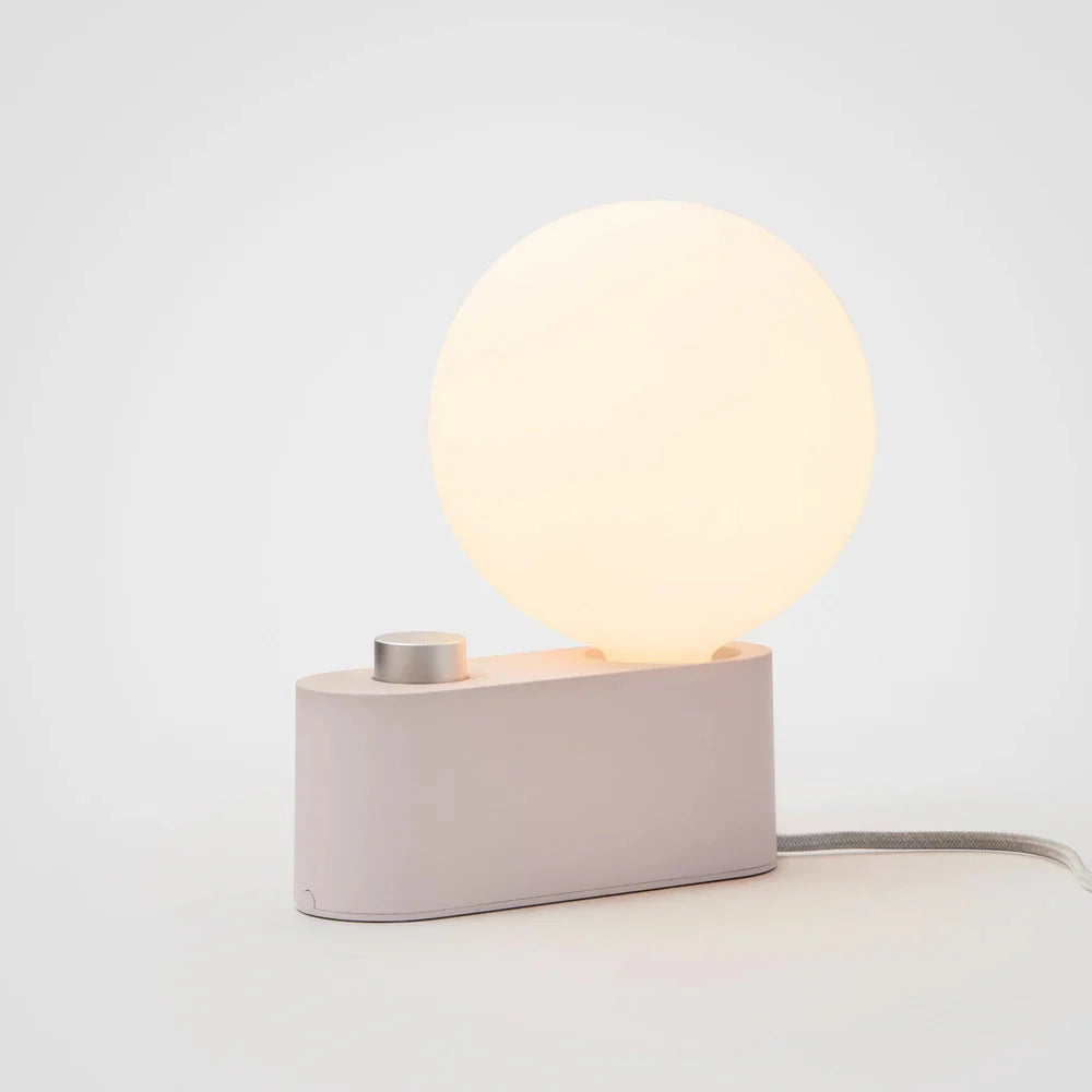 Minimalist modern lamp with a glowing round LED bulb and a dimmable control on a rectangular base