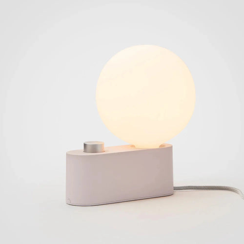 Minimalist modern lamp with a glowing round LED bulb and a dimmable control on a rectangular base