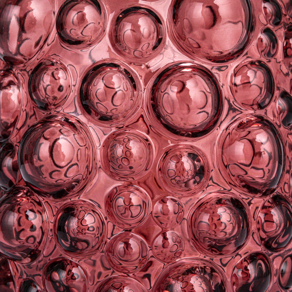 Close-up of textured pink glass with raised bubble patterns, showcasing artistic home decor detail.