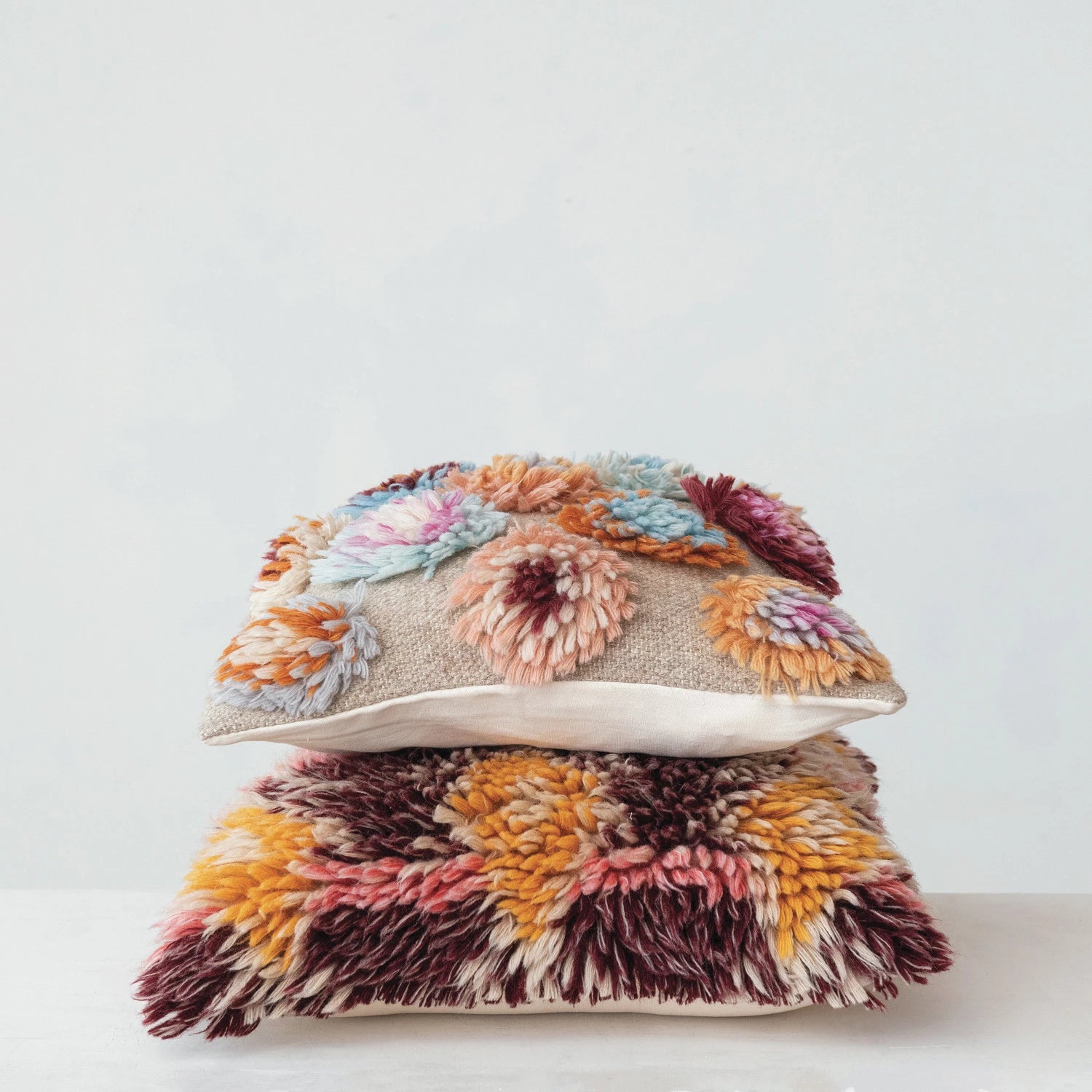 Stacked multicolor wool pillows with shag and floral textured patterns for home decor and sofa accents