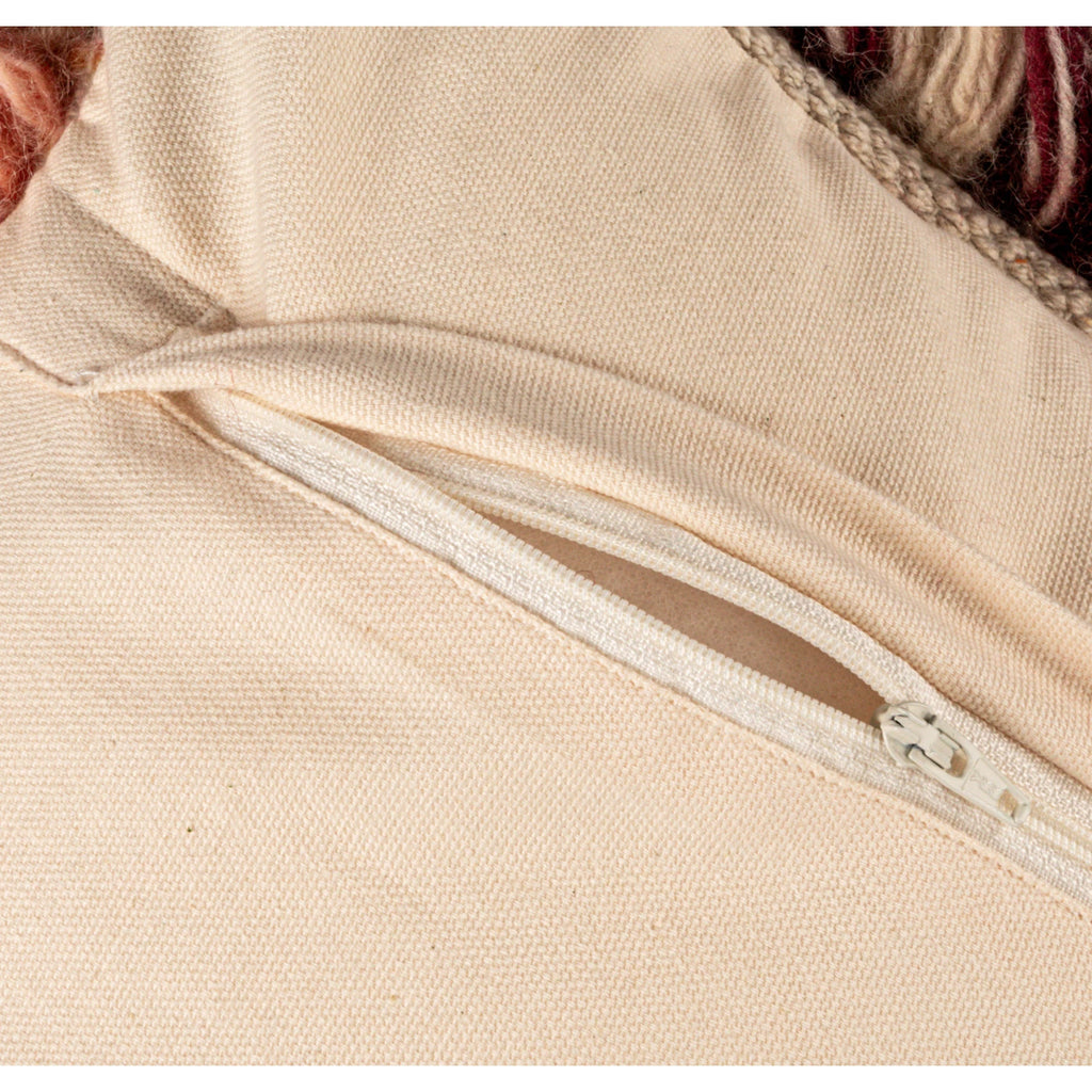 Close-up of a cream fabric pillow cover with a white zipper partially open on the back side.