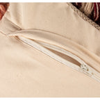 Close-up of a cream fabric pillow cover with a white zipper partially open on the back side.