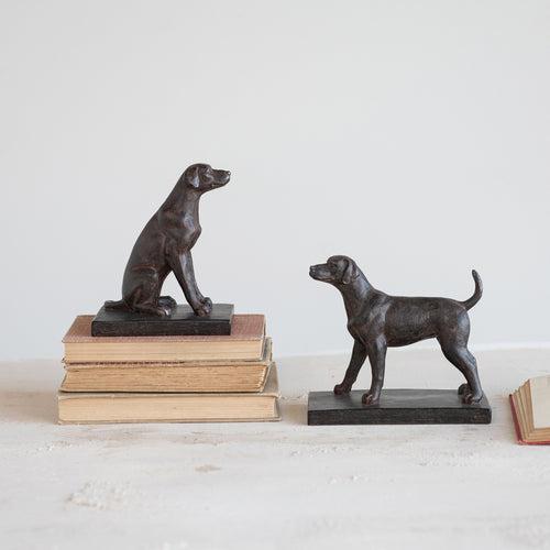 Two black dog sculptures on books against a white background
