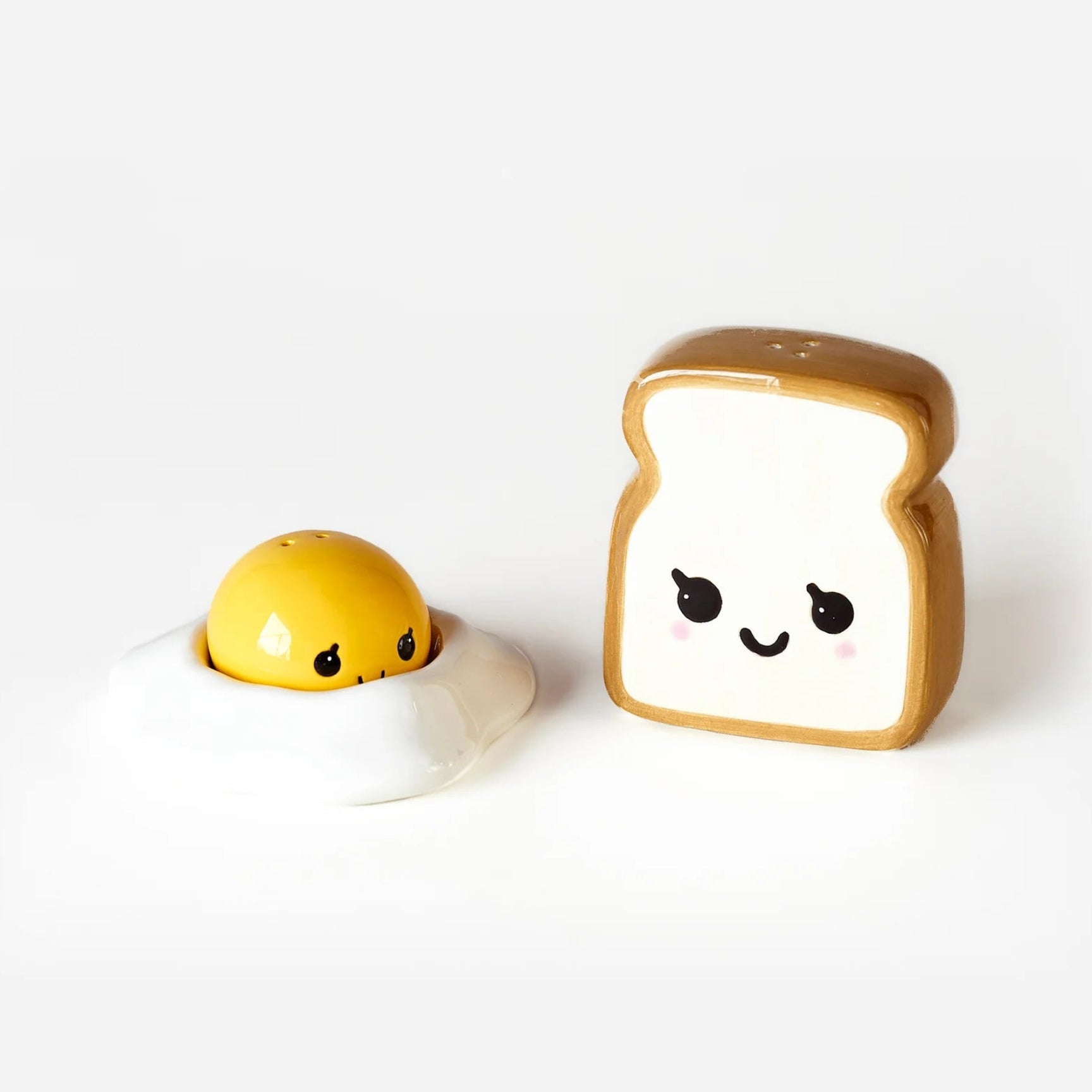 Kawaii-style ceramic salt and pepper shakers shaped like a fried egg and a slice of toast with cute cartoon faces, shown on a clean white background.