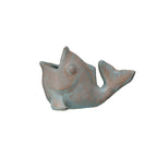 A small fish-shaped decorative object with a distressed metallic finish, featuring a mix of muted teal-blue and warm bronze-brown tones, isolated on a white background.