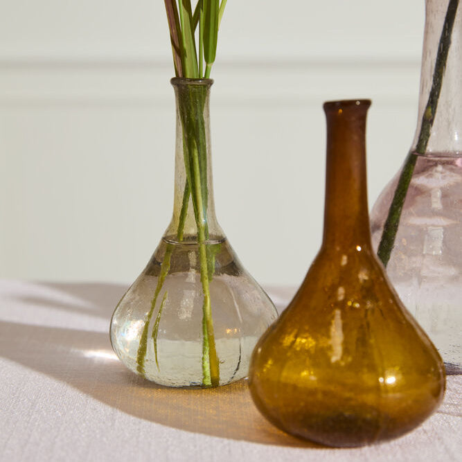 Three glass vases of different colors on a light surface with a neutral background