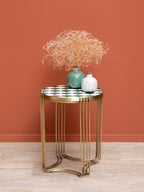 Round side table with ceramic tile top and gold metal legs, styled with decorative vases and dried flowers.
