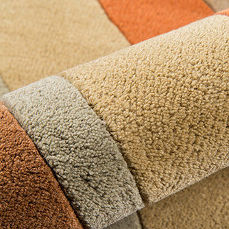 Close-up of textured carpet samples in beige, orange, and brown.