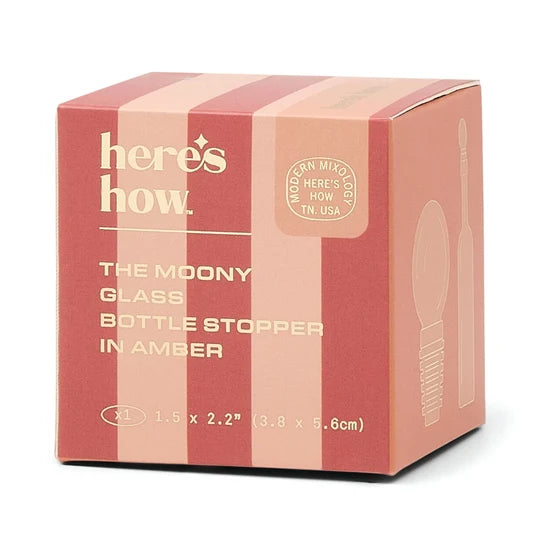 A square cardboard box for a bottle stopper, shown on a clean white background. The box has vertical pink and peach stripes and printed text reading 'here's how.