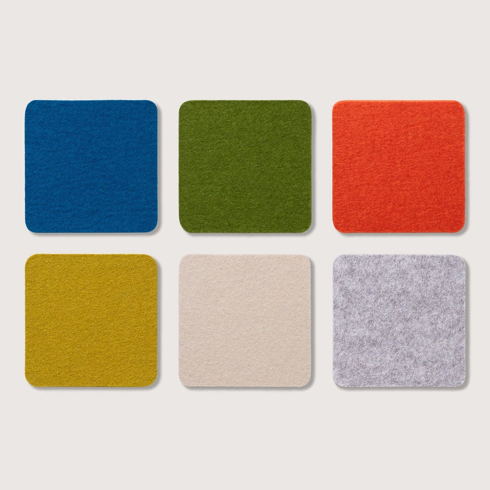 Six square felt coasters in blue, green, orange, yellow, cream, and light gray, arranged in a two-by-three grid on a light beige background.