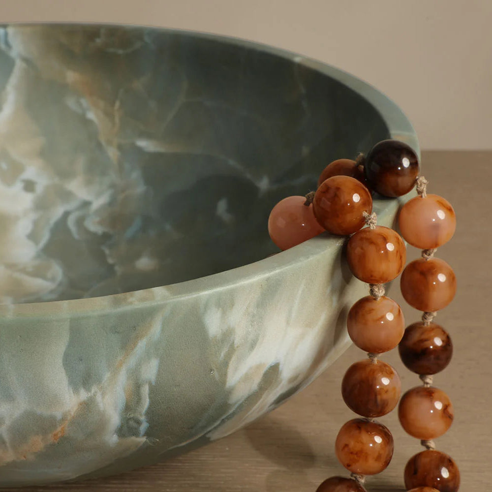 Necklace with brown and orange beads on a marble surface