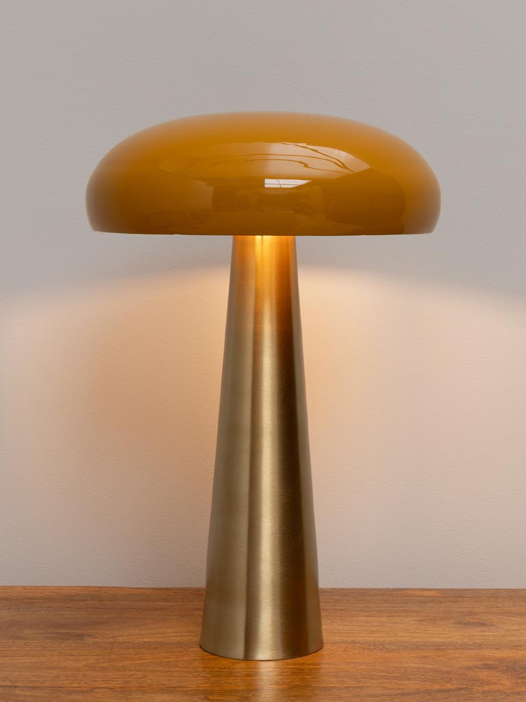 Sleek modern table lamp with a tall brass base and a smooth yellow rounded shade on a wooden surface.