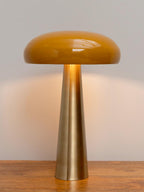 Sleek modern table lamp with a tall brass base and a smooth yellow rounded shade on a wooden surface.
