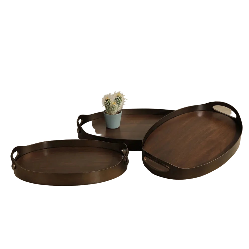 Three oval dark wood serving trays with integrated handles, arranged on a beige tabletop against a neutral beige wall, with a small potted cactus on the center tray.