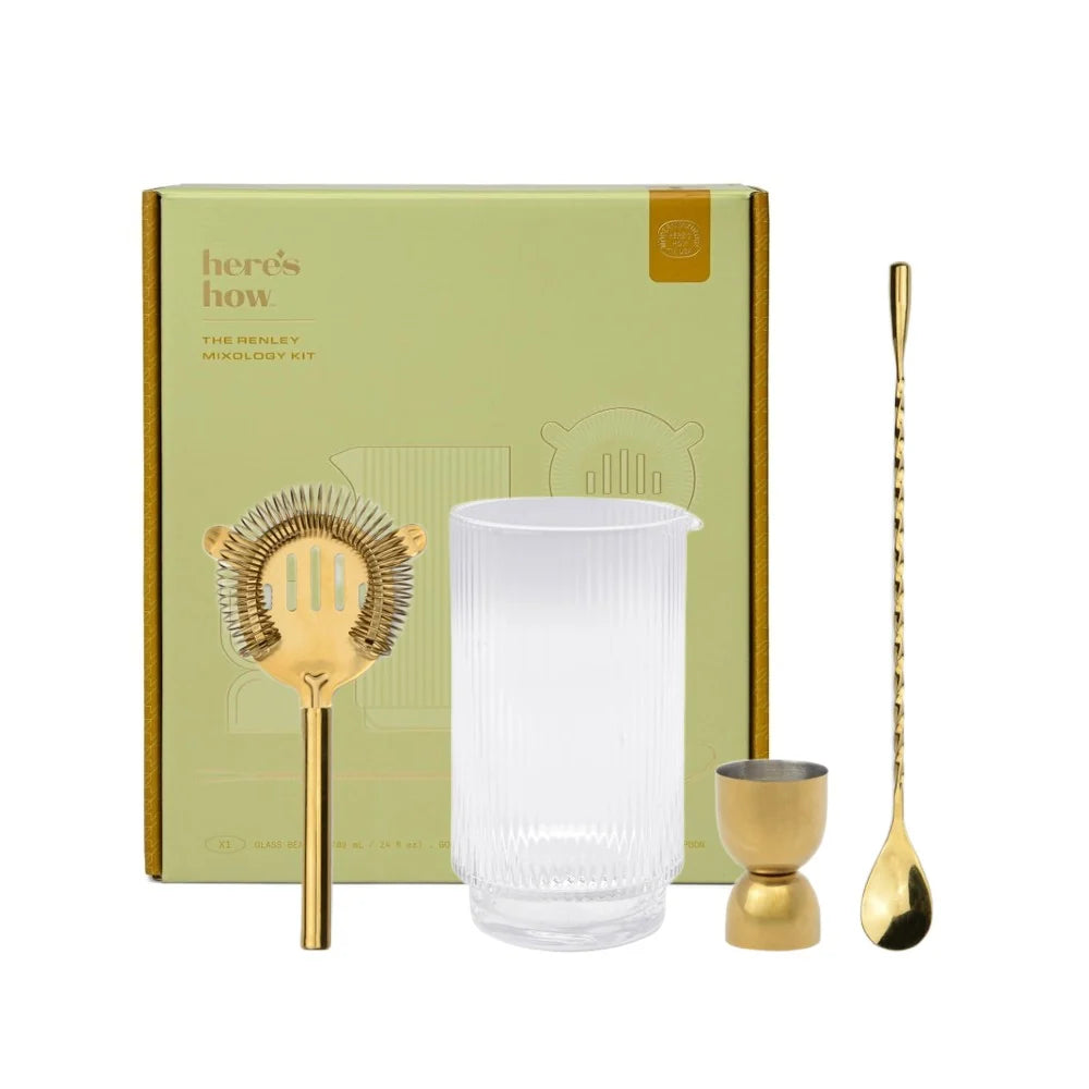 Bartender kit with gold tools and a clear glass container in front of a branded box.
