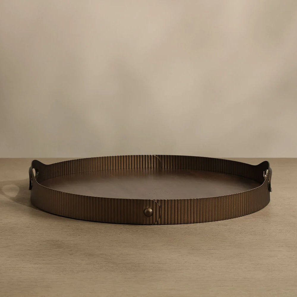 Bronze decorative tray on a beige surface with a beige background