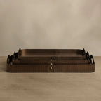 Three nested rectangular trays with a dark brown ribbed texture and integrated handles, displayed on a neutral beige surface against a matching background.