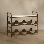 A mid-century modern metal shoe rack with a white upholstered seat and a bronze-finished frame, set against a warm beige background.